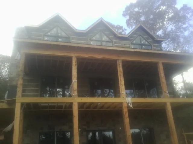 Dormers and porch framing on a large log home under construction — Roof Coating work by our crew in Jennings